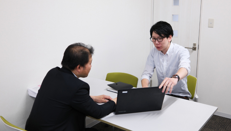 パソコンを見ながら商談をする男性